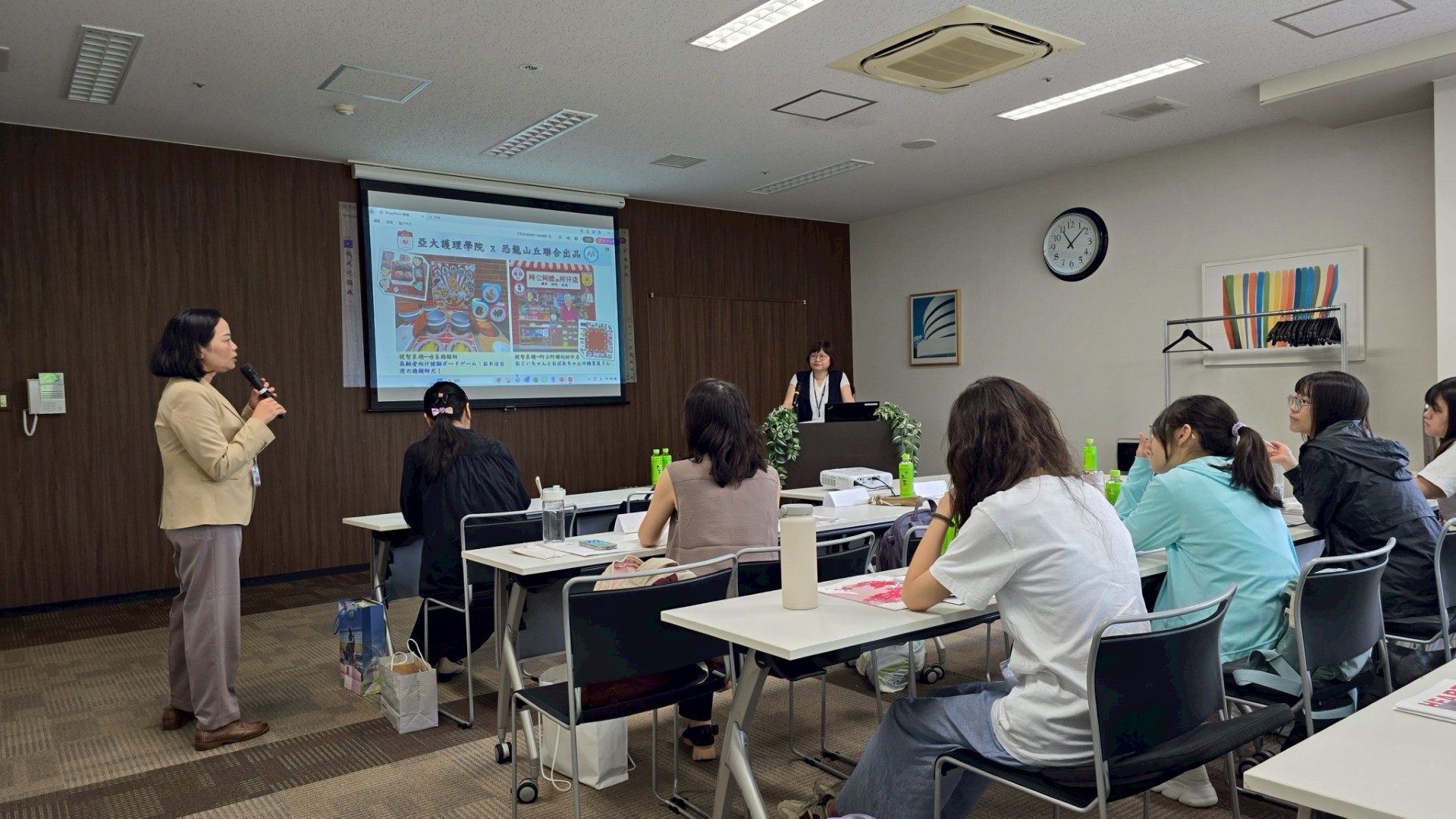 亞大護理學院院長吳樺姍(站立者右)，分享亞大護理學院連續10年獲教育部大學補助，執行「社會處方箋賦能社區」社會責任實踐計畫成果。